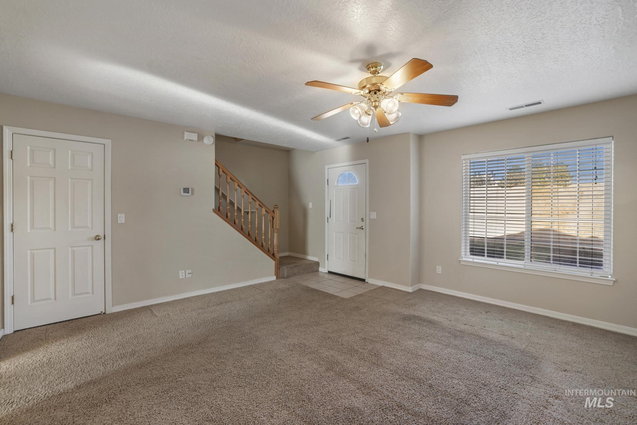 1935 Hampton Way Twin Falls, ID 83301 - Photo 18 of 25 Unfurnished living room featuring light colored carpet, stairs, a textured ceiling, and a ceiling fan