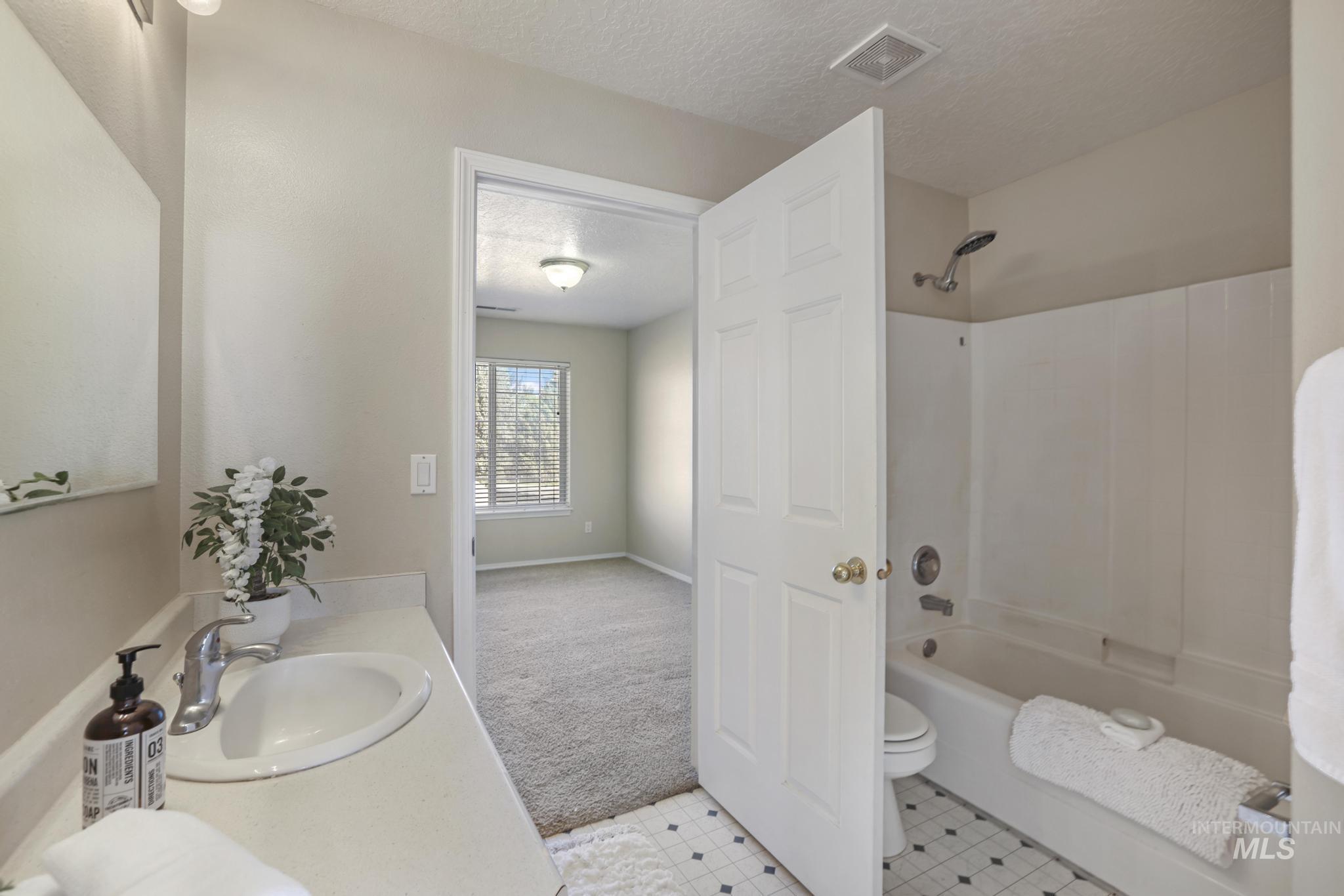 1935 Hampton Way Twin Falls, ID 83301 - Photo 21 of 25 Full bathroom featuring a textured ceiling, bathing tub / shower combination, vanity, and light carpet