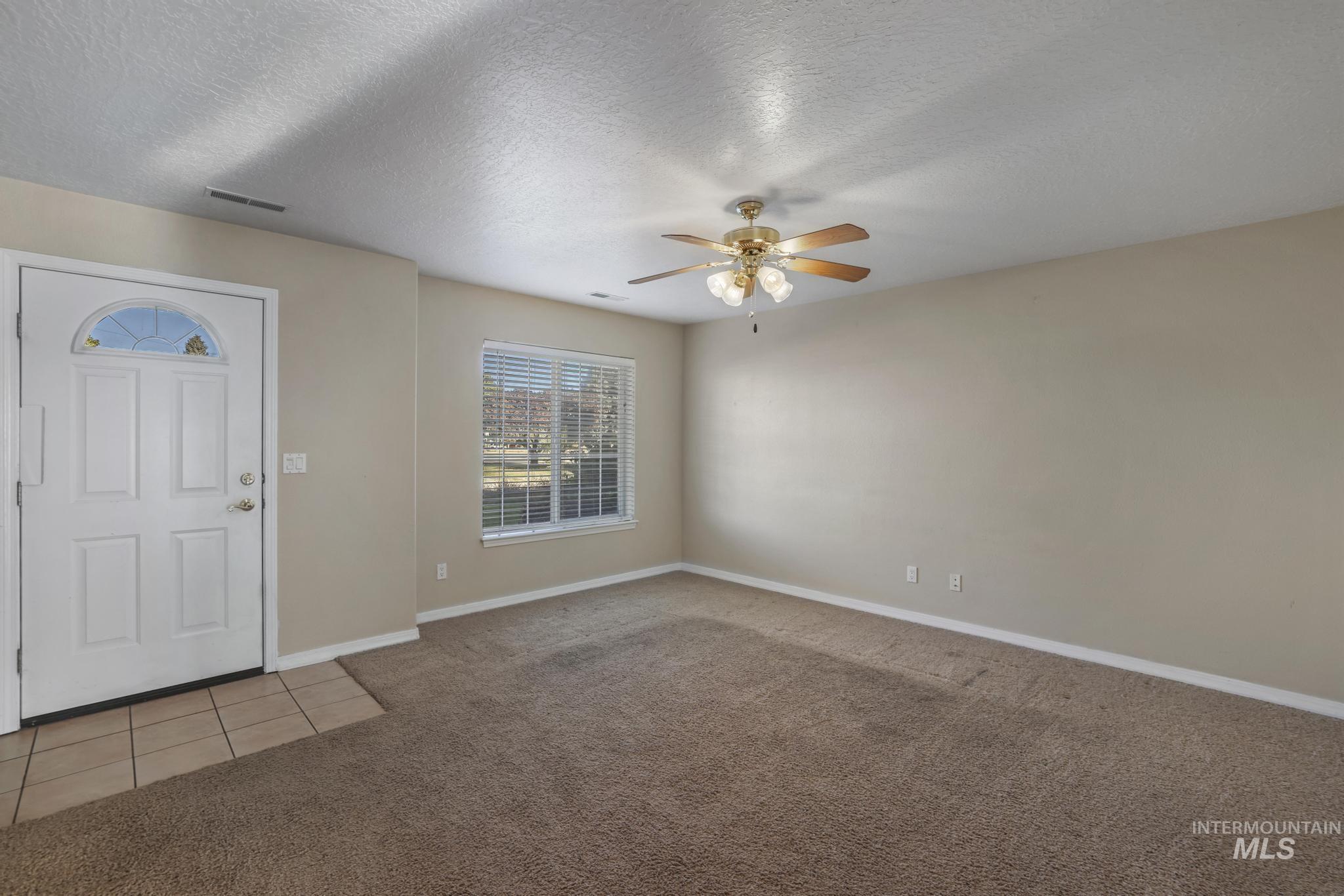 1935 Hampton Way Twin Falls, ID 83301 - Photo 6 of 25 Foyer entrance with light colored carpet, a textured ceiling, light tile patterned flooring, and ceiling fan