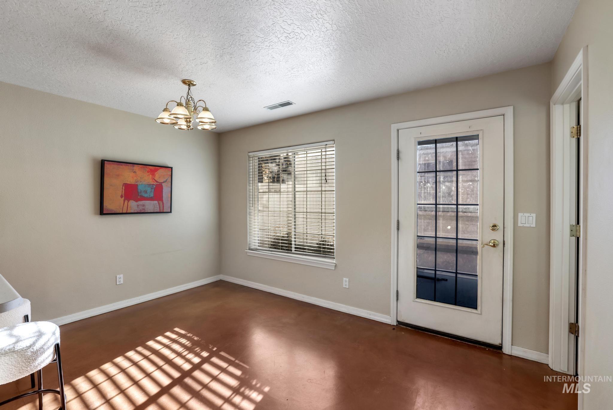 1935 Hampton Way Twin Falls, ID 83301 - Photo 7 of 25 Unfurnished room with a textured ceiling, finished concrete floors, and a chandelier