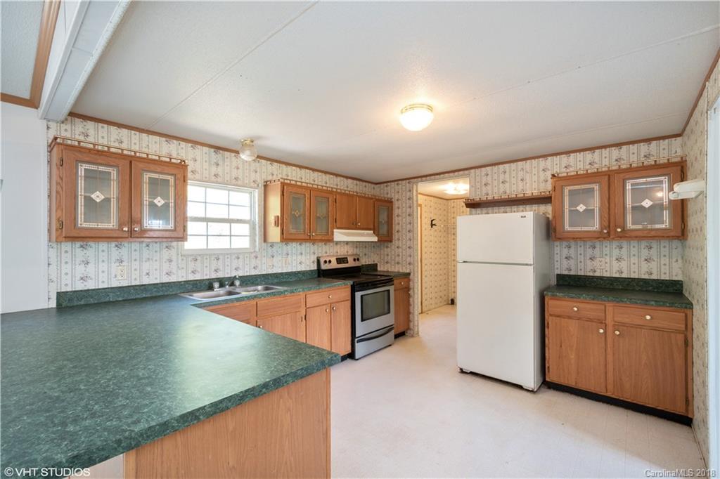 662 Lake Adger Road Mill Spring, NC 28756 - Photo 4 of 20 a kitchen with granite countertop a stove and a refrigerator
