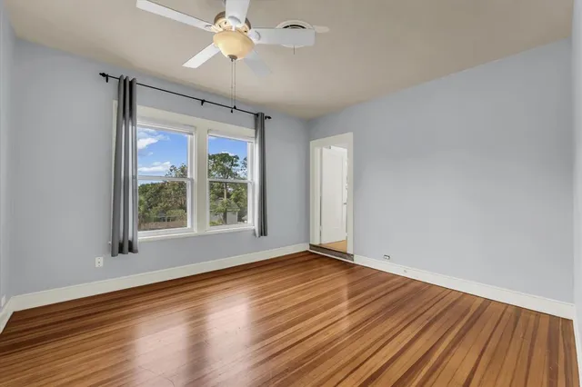 a view of an empty room with wooden floor and a window