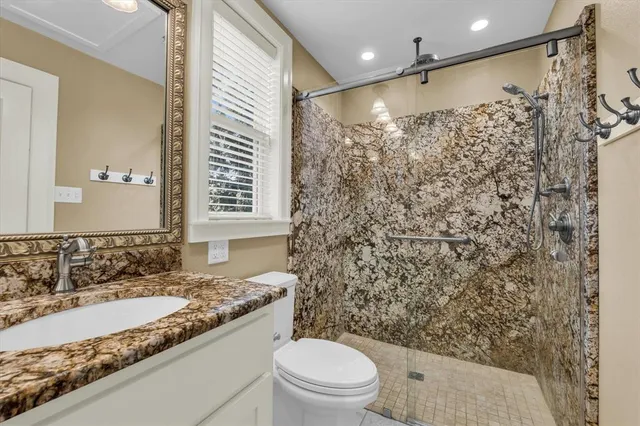 a bathroom with a granite countertop sink toilet and shower