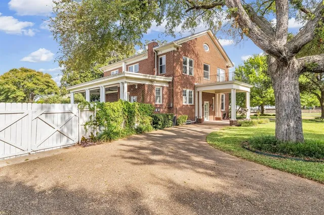 a front view of a house with a garden and trees