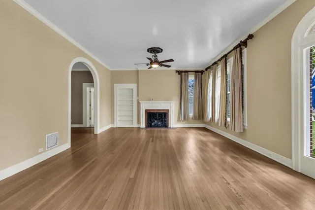 a view of an empty room with wooden floor fireplace and a window