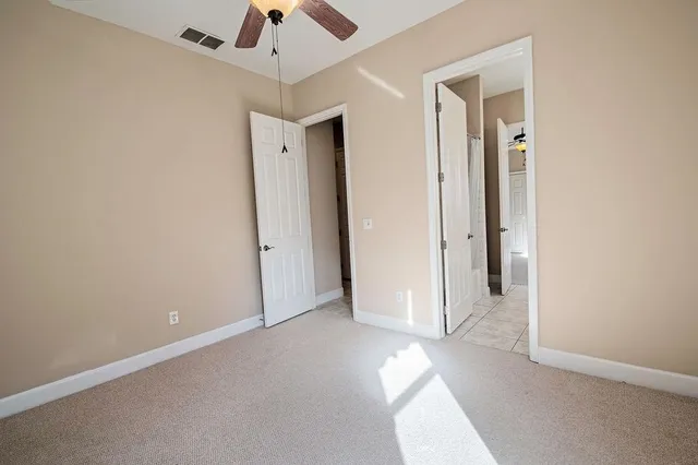 an empty room with a ceiling fan and carpet