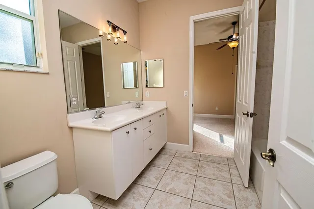 a bathroom with a double vanity sink toilet and mirror