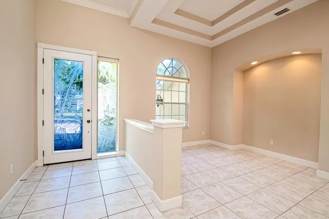 a view of an empty room with window and chandelier fan