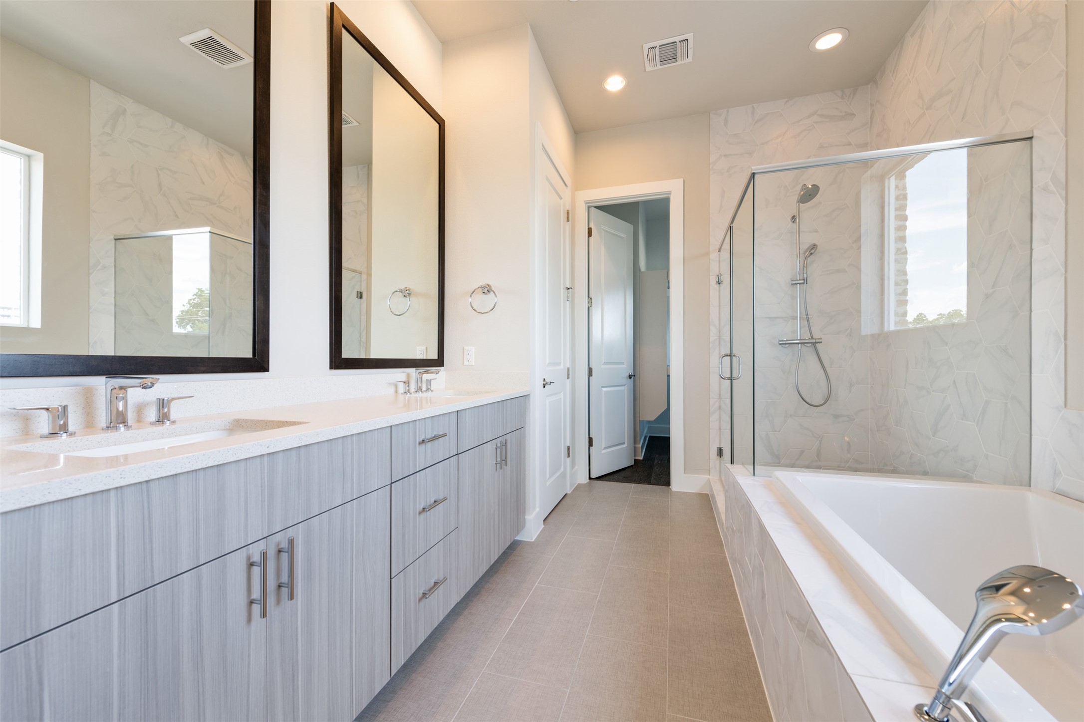1308 Tinnin Ford Road, Unit 1 Austin, TX 78741 - Photo 11 of 21 a spacious bathroom with a double vanity sink a mirror a bathtub and shower