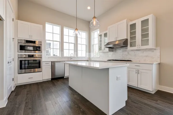 a kitchen with stainless steel appliances granite countertop a stove a sink and a microwave
