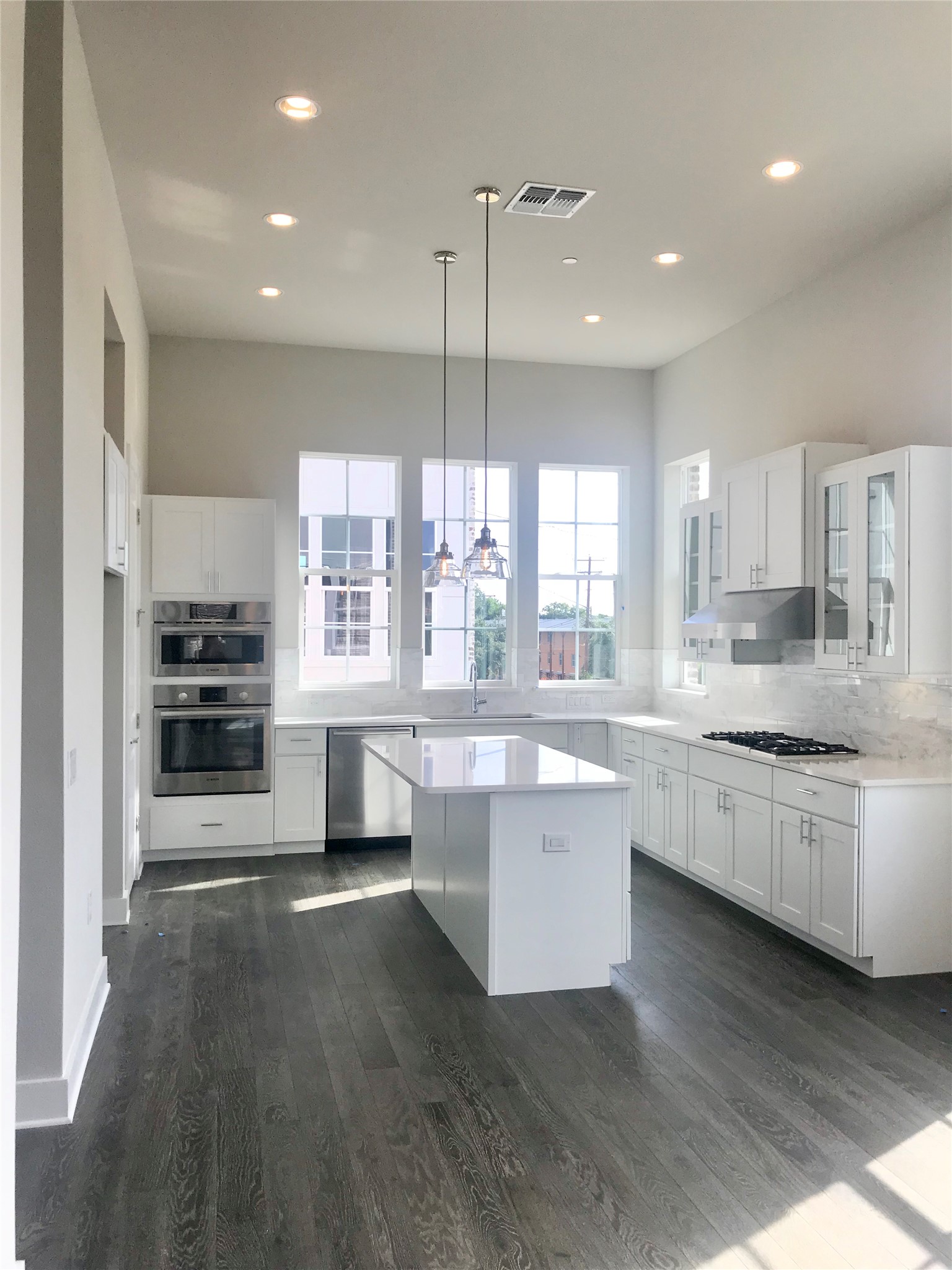 1308 Tinnin Ford Road, Unit 1 Austin, TX 78741 - Photo 7 of 21 a large kitchen with kitchen island a stove a sink a refrigerator and white cabinets with wooden floor