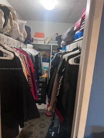 a view of walk in closet with clothes and shoes
