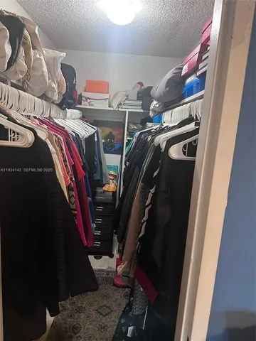 a view of walk in closet with clothes and shoes