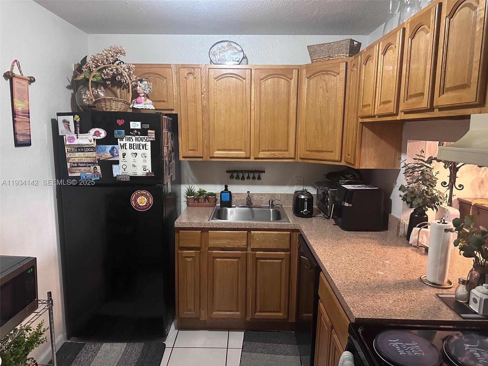 9974 Southwest 88th Street, Unit 1028 Miami, FL 33176 - Photo 5 of 24 a kitchen with a sink refrigerator and cabinets