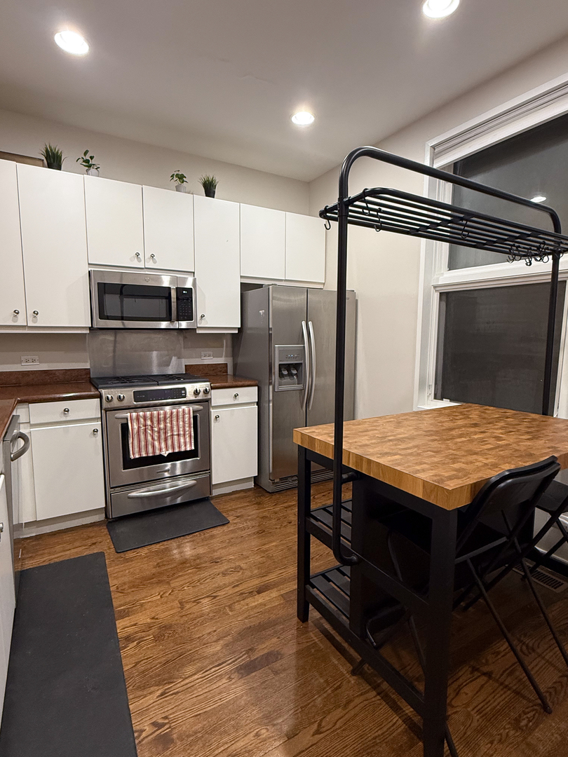 943 West Huron Street, Unit E Chicago, IL 60642 - Photo 2 of 22 a kitchen with stainless steel appliances kitchen island granite countertop a table chairs and a refrigerator