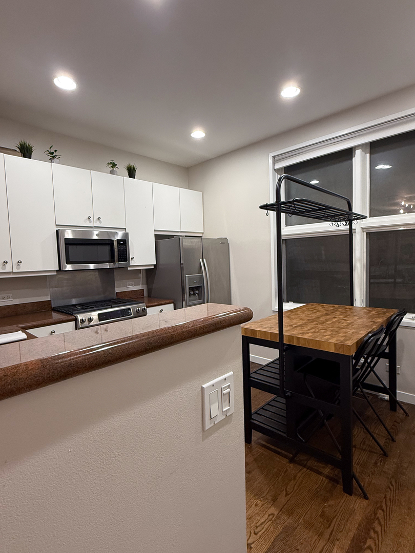943 West Huron Street, Unit E Chicago, IL 60642 - Photo 3 of 22 a kitchen with kitchen island a wooden floor and white cabinets