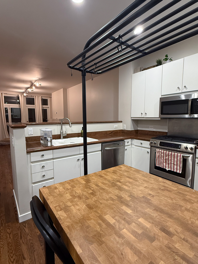 943 West Huron Street, Unit E Chicago, IL 60642 - Photo 4 of 22 a kitchen with stainless steel appliances kitchen island granite countertop a stove and white cabinets