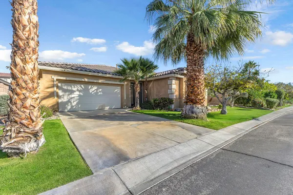 a view of a house with a yard and palm trees