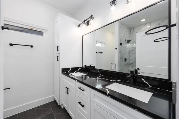 a bathroom with a granite countertop sink a mirror and a shower