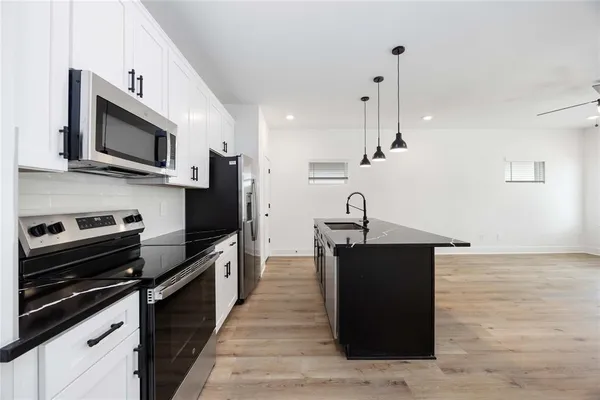 a kitchen with stainless steel appliances kitchen island granite countertop a stove a sink and a microwave