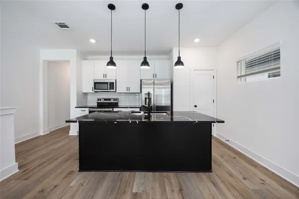 a kitchen with stainless steel appliances granite countertop a sink a stove and a wooden floor