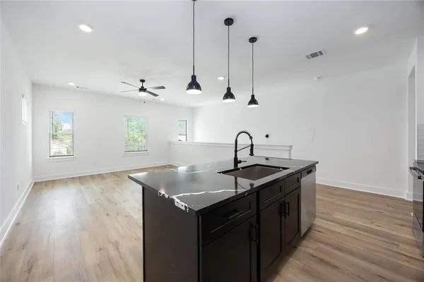 a kitchen with stainless steel appliances granite countertop a sink a window and wooden floor