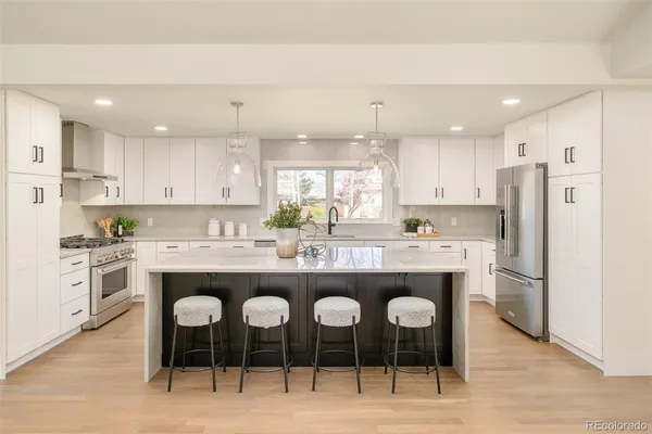 a kitchen with stainless steel appliances a sink a stove a refrigerator cabinets and a window