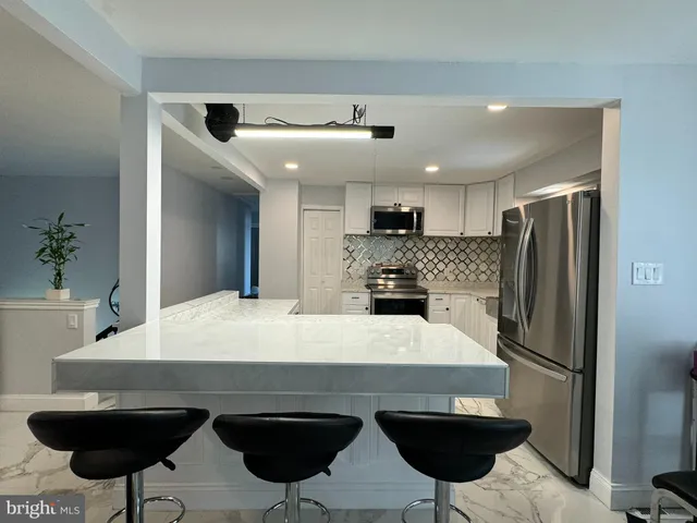 a kitchen with stainless steel appliances a dining table chairs sink and refrigerator