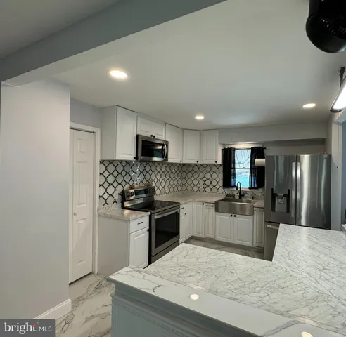 a kitchen with stainless steel appliances kitchen island granite countertop a sink stove and refrigerator