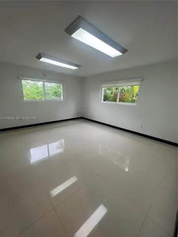 an empty room with windows and ceiling fan