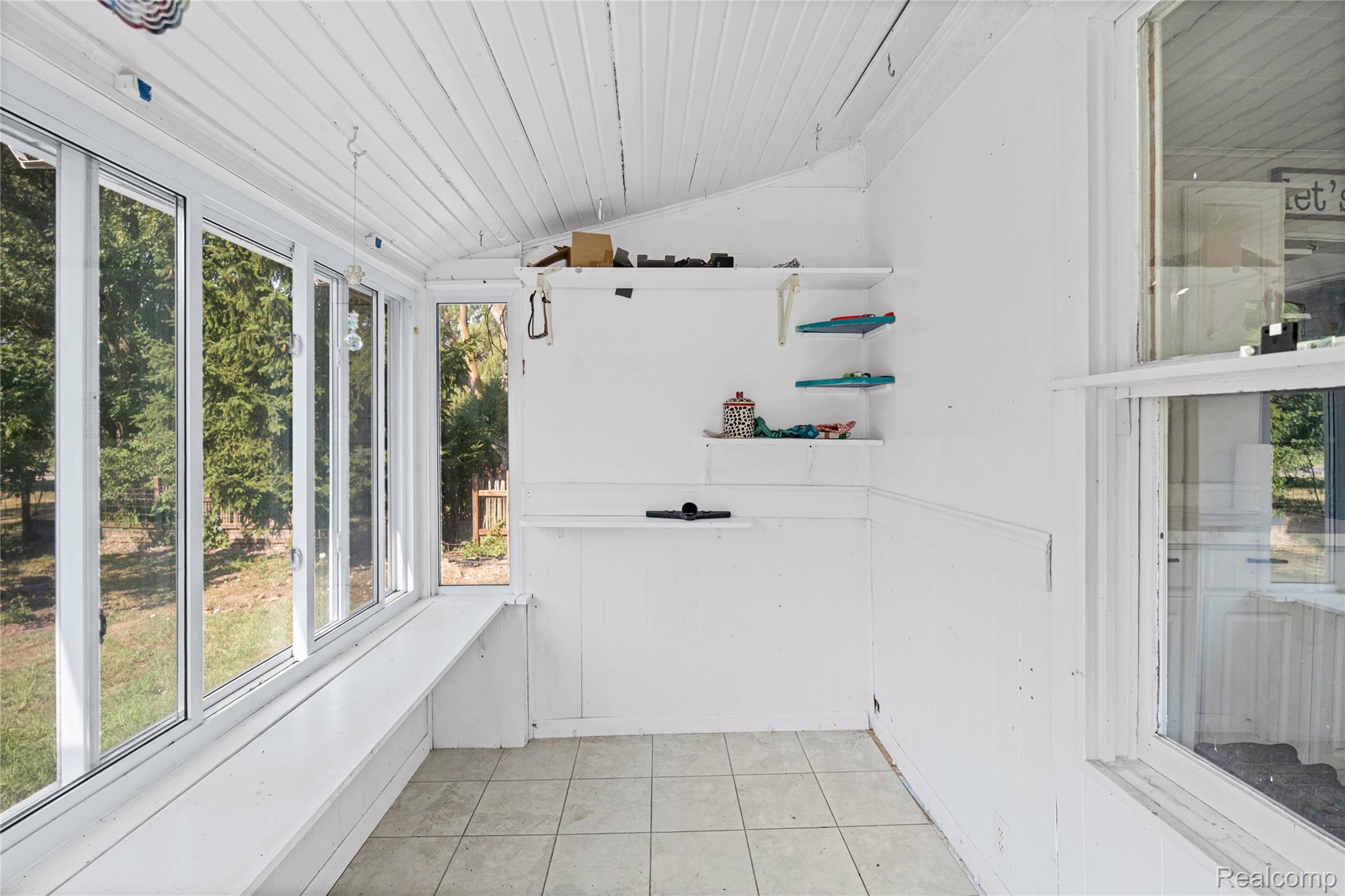1175 South Morrish Road Flint, MI 48532 - Photo 37 of 72 Sunroom featuring extensive window-lines, white paneled walls, a sloped paneled ceiling, and tiled flooring