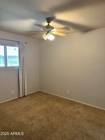 an empty room with windows and fan