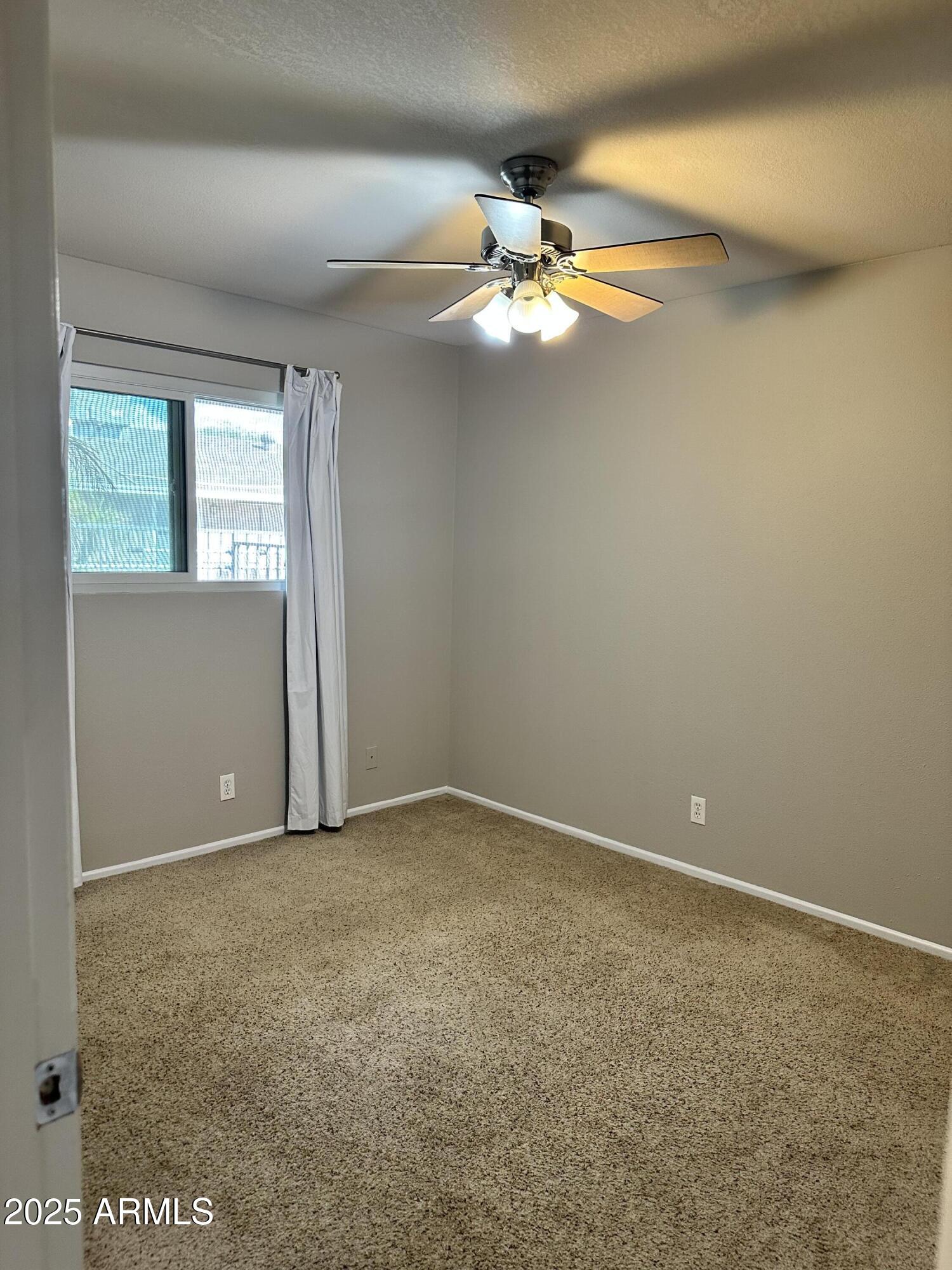 2525 South College Avenue, Unit 2 Tempe, AZ 85282 - Photo 8 of 13 an empty room with a chandelier fan and windows