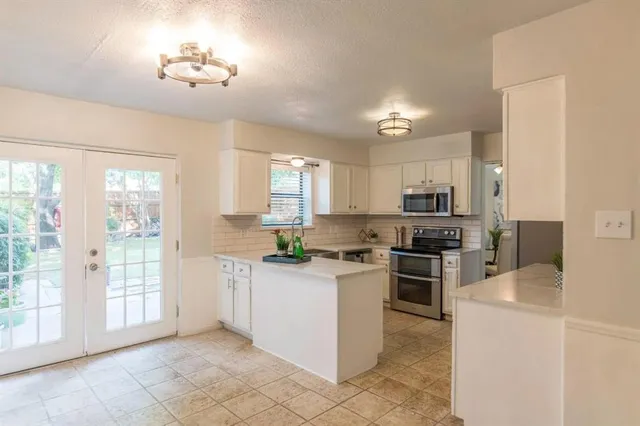a kitchen with stainless steel appliances a refrigerator sink and white cabinets