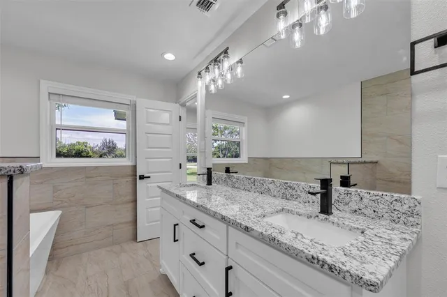 a bathroom with a granite countertop sink a mirror and shower