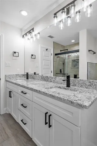 a bathroom with a granite countertop sink a large mirror and shower