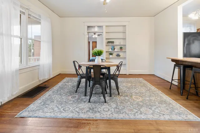 an empty room with wooden floor chandelier fan and windows
