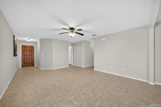 a view of an empty room with a chandelier fan