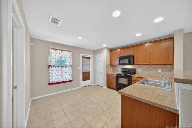 a kitchen with stainless steel appliances granite countertop a stove top oven a sink a refrigerator white cabinets and wooden floor