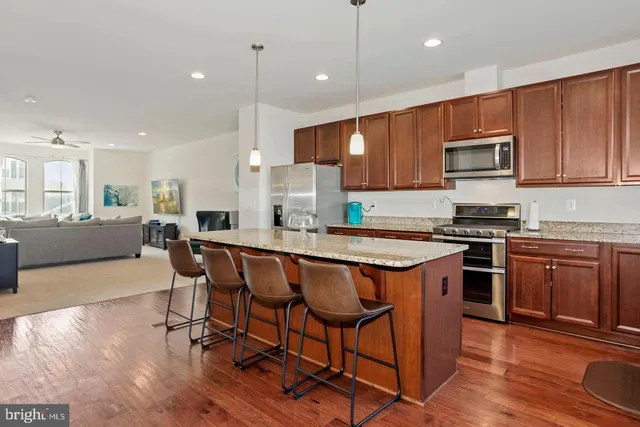 a kitchen with stainless steel appliances granite countertop wooden cabinets a refrigerator a stove a microwave oven a sink with island and chairs