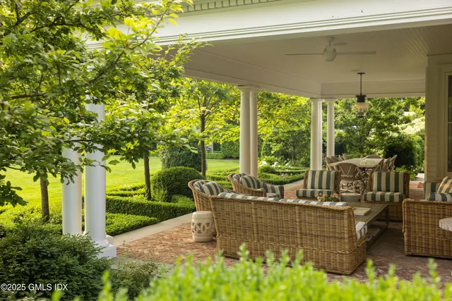 a view of a patio with couches potted plants and large tree