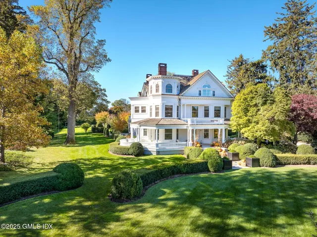 a front view of a house with garden and trees