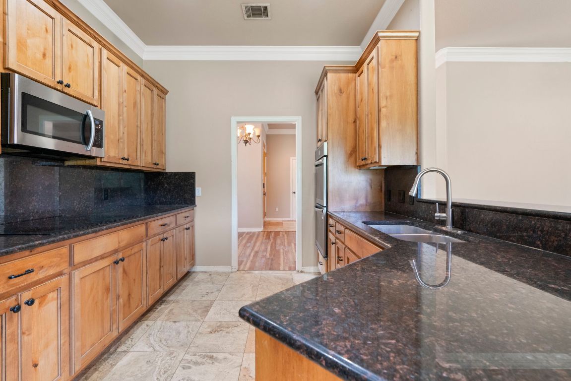 1237 Ridge Harbor Drive Spicewood, TX 78669 - Photo 13 of 40 a kitchen with stainless steel appliances granite countertop a sink a stove and a microwave oven