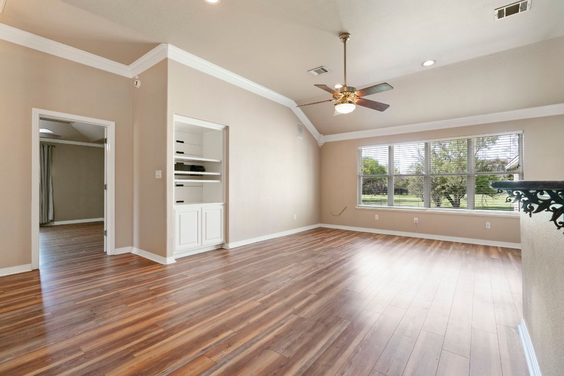 1237 Ridge Harbor Drive Spicewood, TX 78669 - Photo 15 of 40 a view of a room with wooden floor ceiling fan and windows