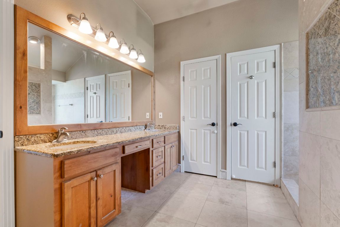 1237 Ridge Harbor Drive Spicewood, TX 78669 - Photo 19 of 40 a bathroom with a granite countertop sink a large mirror and a shower