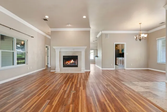 a view of an empty room with wooden floor fireplace and a window