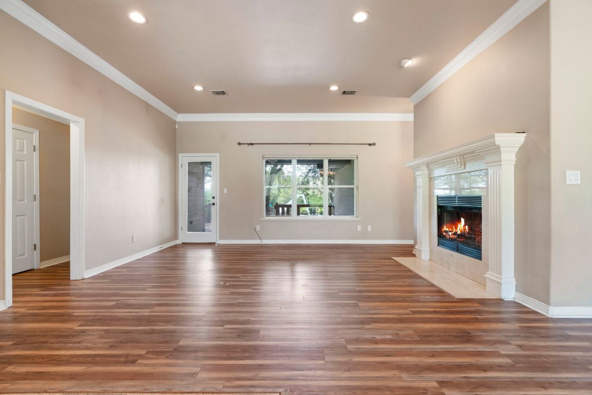 1237 Ridge Harbor Drive Spicewood, TX 78669 - Photo 10 of 40 an empty room with wooden floor fireplace and windows