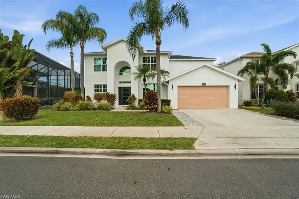 front view of house with a yard and palm trees