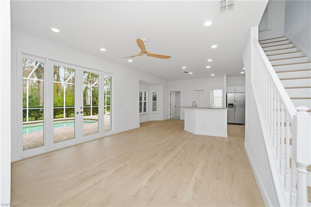 21314 Braxfield Loop Estero, FL 33928 - Photo 18 of 44 a view of an empty room with wooden floor and a kitchen