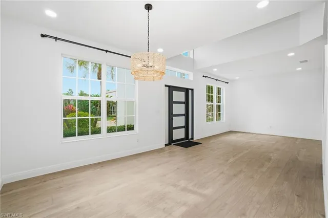 a view of an empty room with a window and chandelier
